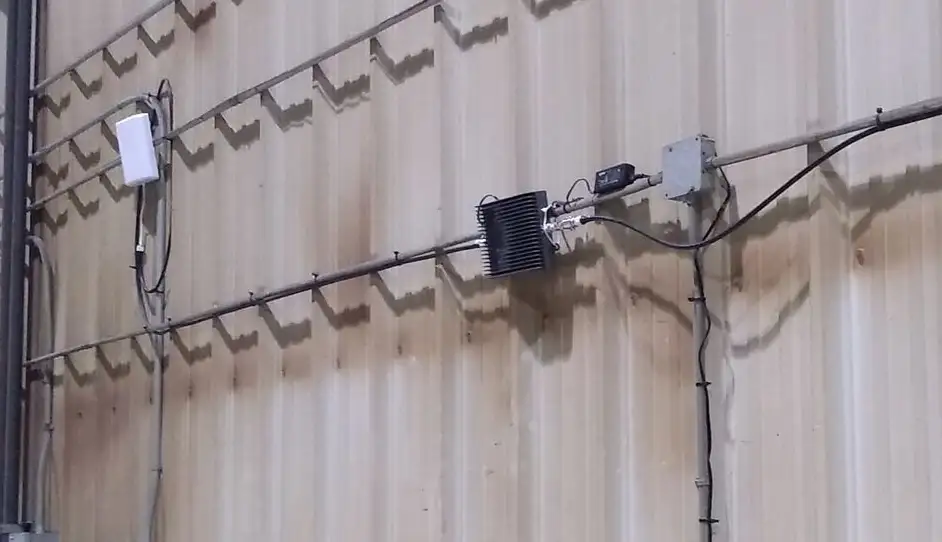 Coax route along a warehouse wall with an inline amplifier and junction boxes.